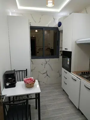 a kitchen with white cabinets and a table with a bowl on it at La maison bleu in Oulad Akkou