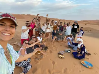 a group of people posing for a picture in the desert at visitando el desierto in Merzouga