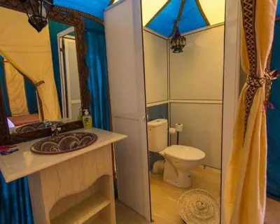 a bathroom with a toilet and a sink and a mirror at Luxurious magic camp in Merzouga