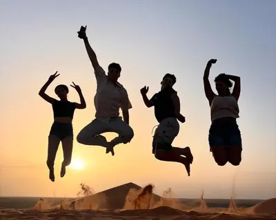 a group of people jumping in the desert at Luxurious magic camp in Merzouga