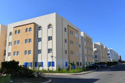 an apartment building on a street with cars parked at Tifawt in Oulad Akkou