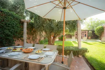 a table with plates of food and an umbrella at Luxueuse villa VALERIA avec gouvernante in Chaibate