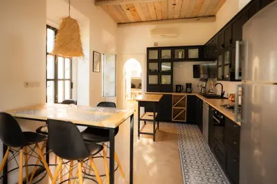 a kitchen with black cabinets and bar stools at Luxueuse villa VALERIA avec gouvernante in Chaibate