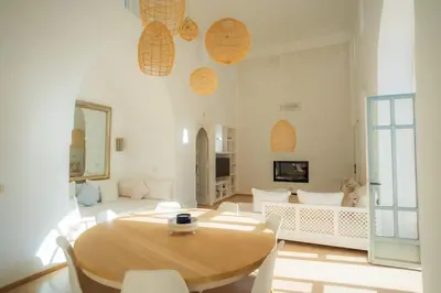 a living room with a wooden table and white chairs at Luxueuse villa VALERIA avec gouvernante in Chaibate
