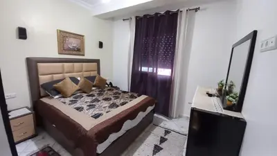 a bedroom with a bed and a desk and a mirror at Appartement in Oulad Akkou