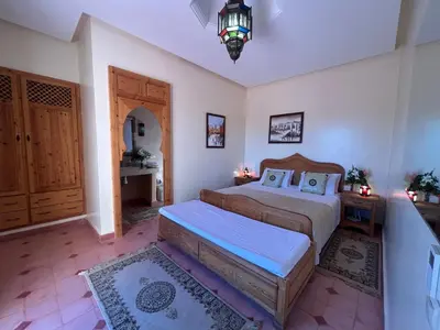 a bedroom with a bed and a table and a door at Villa Essalah & Spa Marrakech in Marrakech