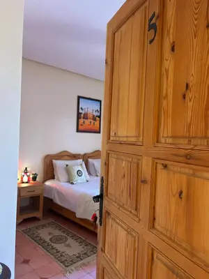 a bedroom with a bed and a wooden door at Villa Essalah & Spa Marrakech in Marrakech