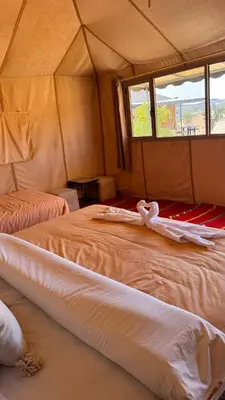 a bedroom with two beds in a tent at Tasnim Désert Camp & Activités in Merzouga
