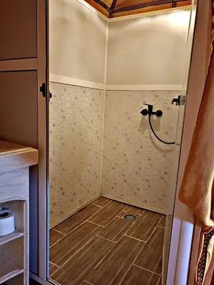 a shower in a small room with a wooden floor at Tasnim Désert Camp & Activités in Merzouga
