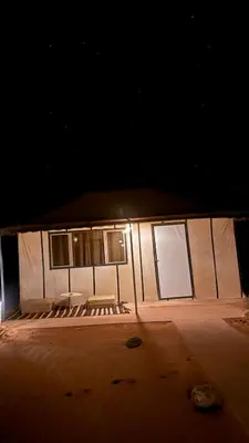 a building with a table and chairs in the dark at Tasnim Désert Camp & Activités in Merzouga