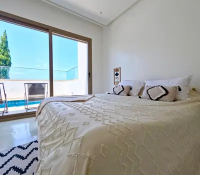 a bedroom with a large bed with a large window at Maison avec 2 piscines vue mer et montagne in Oulad Akkou