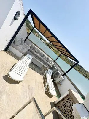 a glass house with a patio and a chair and a table at Maison avec 2 piscines vue mer et montagne in Oulad Akkou