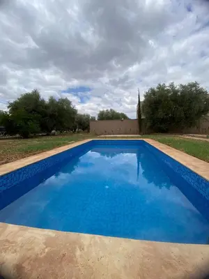 a large blue swimming pool with a church in the background at Villa cherif in Chouiter