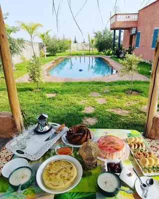 a table with plates of food on it with a pool at DAR MORAD VILLA AVEC PISCINE PRIVEE DANS UNE FERMe in Bou Azza