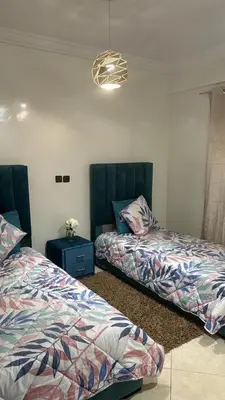 a bedroom with two beds and a blue table at Appartement BM - Béni Mellal in Beni Mellal
