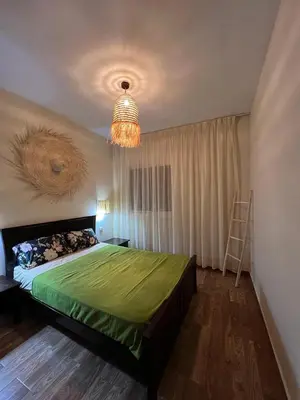 a bedroom with a green bed and a chandelier at Bella vesta in Oulad Akkou