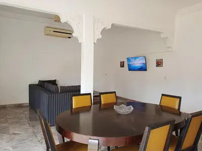 a dining room with a table and chairs and a couch at Riad Elbahi in Marrakech
