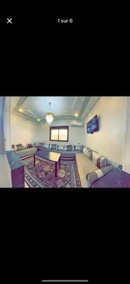 a large room with couches and a table and a rug at Apparemment bien entretenu in Meknès