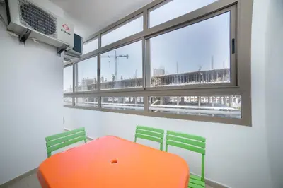 an orange table and two green chairs in a room with a window at Basharly in Oulad Akkou