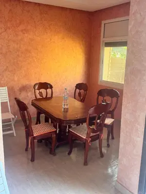 a wooden table and chairs in a room at Petite villa à cap de l eau in Oulad Akkou
