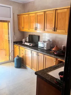 a kitchen with wooden cabinets and a counter top at Petite villa à cap de l eau in Oulad Akkou
