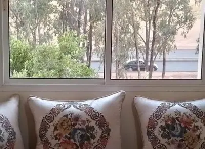 a couch with pillows in front of two windows at Maison heureuse Vue magnifique très proche autoroute in Meknès
