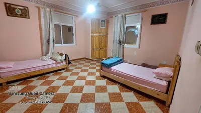 two beds in a room with a checkered floor at شقق محمد in Oulad Akkou