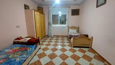 a room with two beds and a checkered floor at شقق محمد in Oulad Akkou