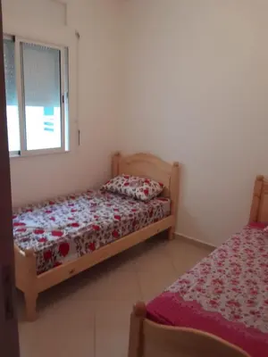 a bedroom with two beds and a window at Alhoceima in Oulad Akkou