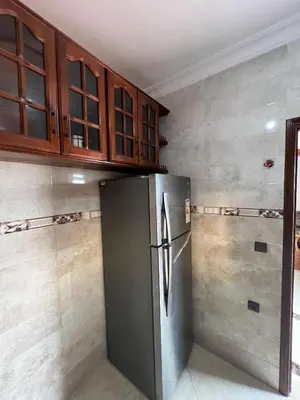 a kitchen with a stainless steel refrigerator and wooden cabinets at Résidence badr in Oulad Akkou