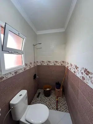 a bathroom with a toilet and a window at Résidence badr in Oulad Akkou