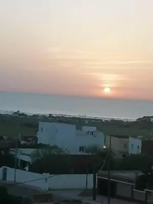 a sunset over a city with the sun in the sky at Résidence badr in Oulad Akkou