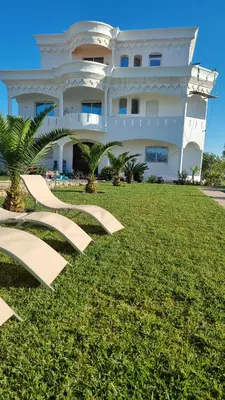 a large white building with stairs in the grass at Palm in Oulad Akkou