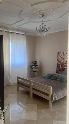 a bedroom with a large bed with a chandelier at Palm in Oulad Akkou