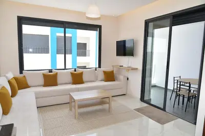 a living room with a white couch and a table at Mehdia Beach in Oulad Akkou