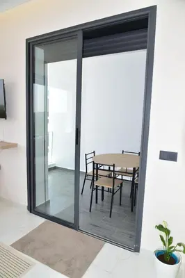 a sliding glass door with a table in a room at Mehdia Beach in Oulad Akkou