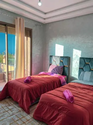 a bedroom with two beds with red sheets and a window at Ourika Luxury Villa in Ourika