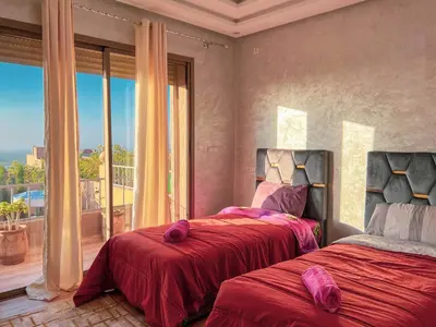 a bedroom with two beds and a large window at Ourika Luxury Villa in Ourika
