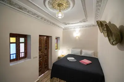 a bedroom with a bed with a black blanket and a window at Riad Fez Unique in Fès