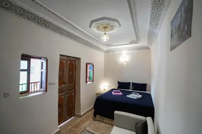 a bedroom with a bed and a chair in a room at Riad Fez Unique in Fès