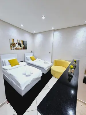 a room with two beds and a yellow chair at Bright & Comfortable Marrakech Duplex in Oulad Akkou