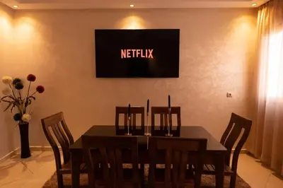 a dining room table with chairs and a television on the wall at Bright & Comfortable Marrakech Duplex in Oulad Akkou