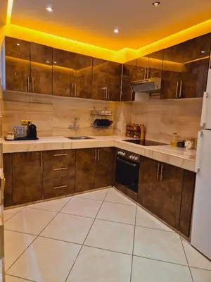 a kitchen with wooden cabinets and a white refrigerator at Bright & Comfortable Marrakech Duplex in Oulad Akkou