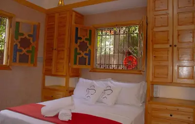 a bedroom with a bed with white sheets and windows at Bab Jbel in Ourika