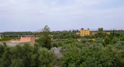a town with a yellow building in the middle of trees at Bab Jbel in Ourika