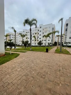 a park with palm trees in front of a building at Brise de Tamaris in Oulad Akkou
