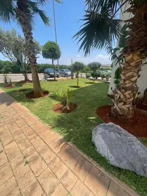 a park with a palm tree and a rock at Brise de Tamaris in Oulad Akkou