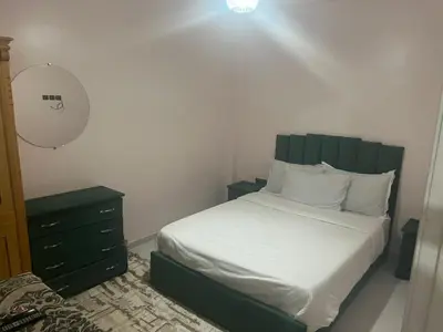 a bedroom with a bed with a green headboard and a dresser at dakhla extreme in Oulad Akkou