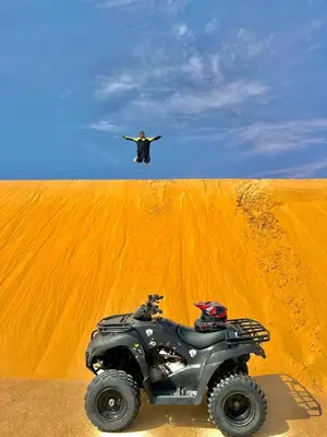 a man standing on top of a desert with a atv at dakhla extreme in Oulad Akkou