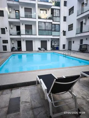 a swimming pool in front of a apartment building at Appartement luxe in Oulad Akkou